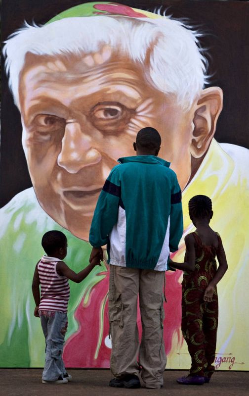 A family looks at a portrait of Pope Benedict in Yaounde