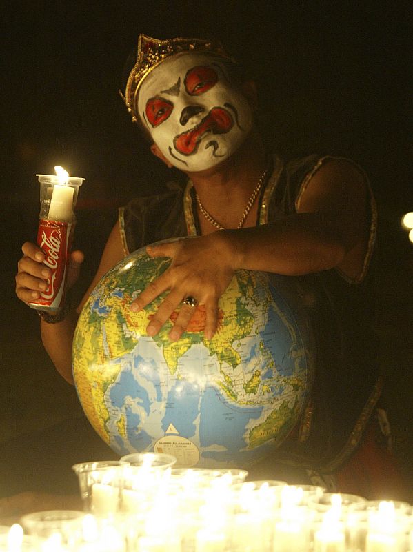 Man wearing traditional costume holds candle to support Earth Hour in Jakarta