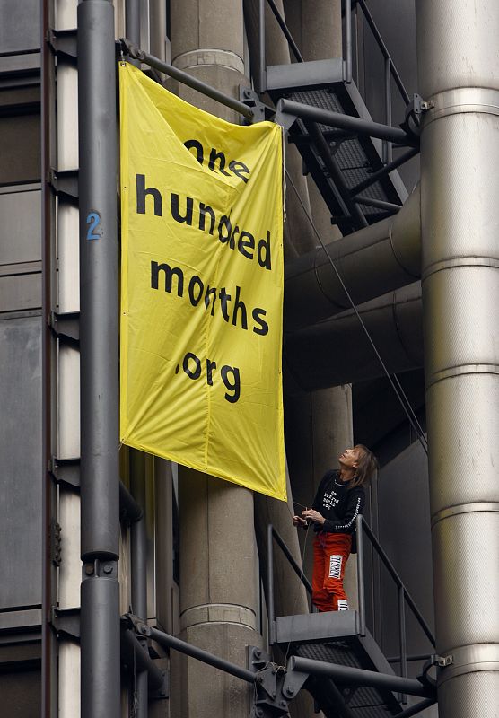 Alain Robert coloca un cartel en el edificio Lloyds, al que ha escalado durante una de las protestas