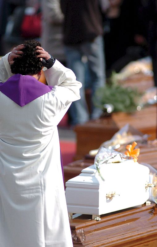 Un sacerdote se emociona ante la visión de un pequeño ataúd en L'Aquila.