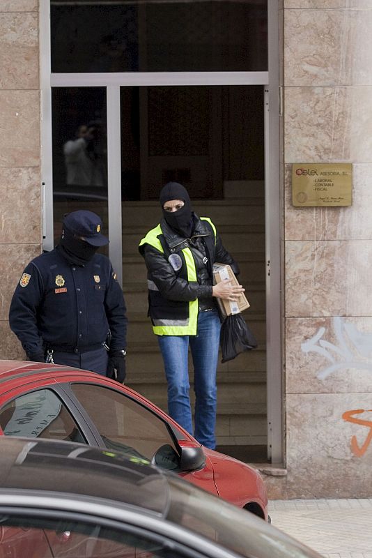 Una Agente de la Policía Nacional sale con material incautado durante el registro del domicilio de uno de los detenidos en la calle Isanza de la capital alavesa.