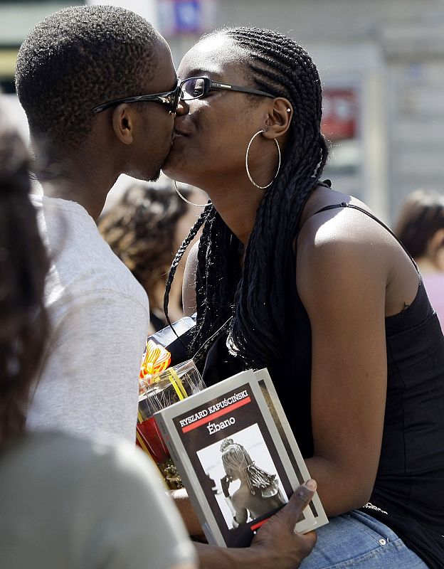 Una pareja se besa tras intercambiar una rosa por un libro, tal y como manda la tradición del día de San Jordi.