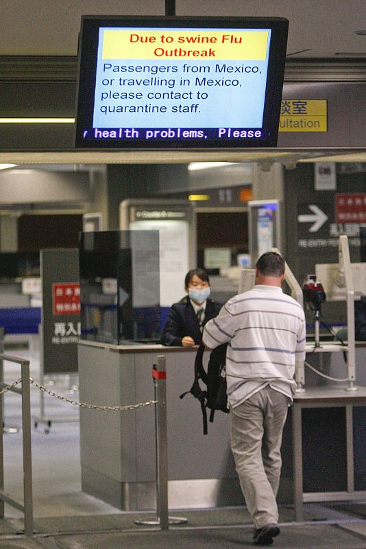 Un viajero pas junto a una inspectora en la puerta de llegadas del aeropuerto internacional de Narita, al este de Tokio