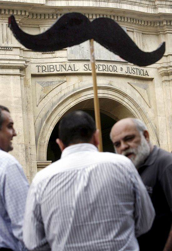 Unos manifestantes contrarios al presidente Camps exhiben un gran bigote a las puertas del TSJ de Valencia, donde se han vivido momentos de tensión.