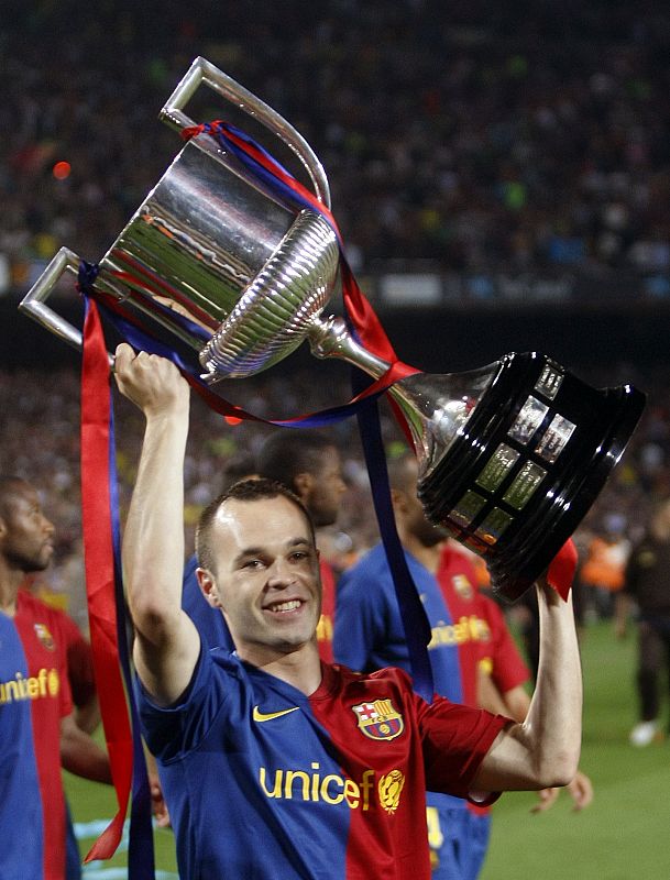 Barcelona's Andres Iniesta holds up the Spanish first division soccer league trophy at Camp Nou stadium in Barcelona