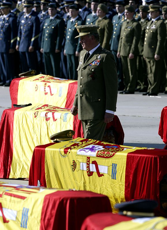 El rey Juan Carlos camina entre los féretros.