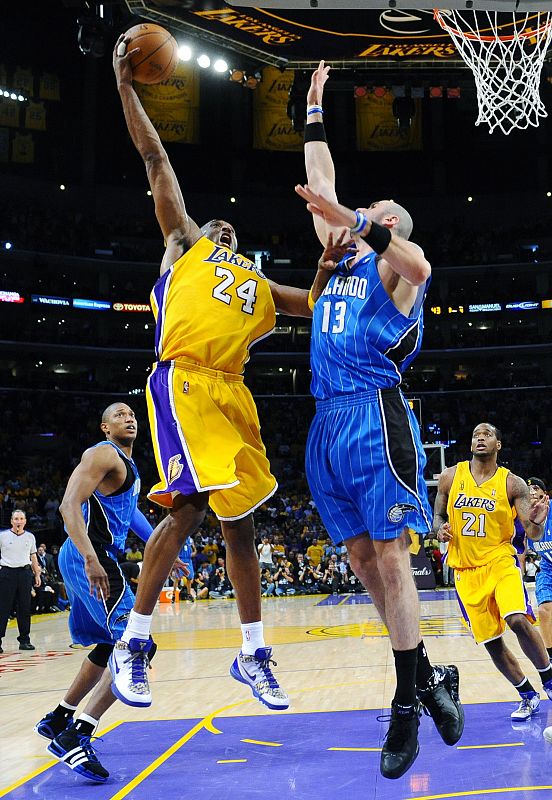 El jugador de los Ángeles Lakers, Kobe Bryant, trata de encestar defendido por Gortat, de los Orlando Magic durante el primer partido de la final de la NBA.