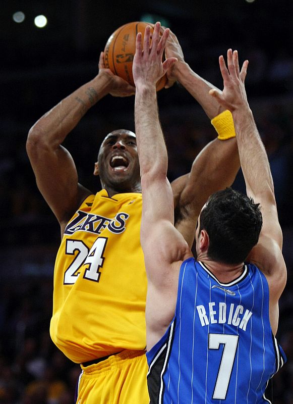 El jugador de los Ángeles Lakers, Kobe Bryant, trata de encestar ante Redick, de los Orlando Magic durante el primer partido de la final de la NBA.