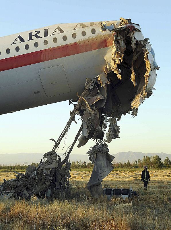 An official stands beside the wreckage of a passenger airplane in Mashhad