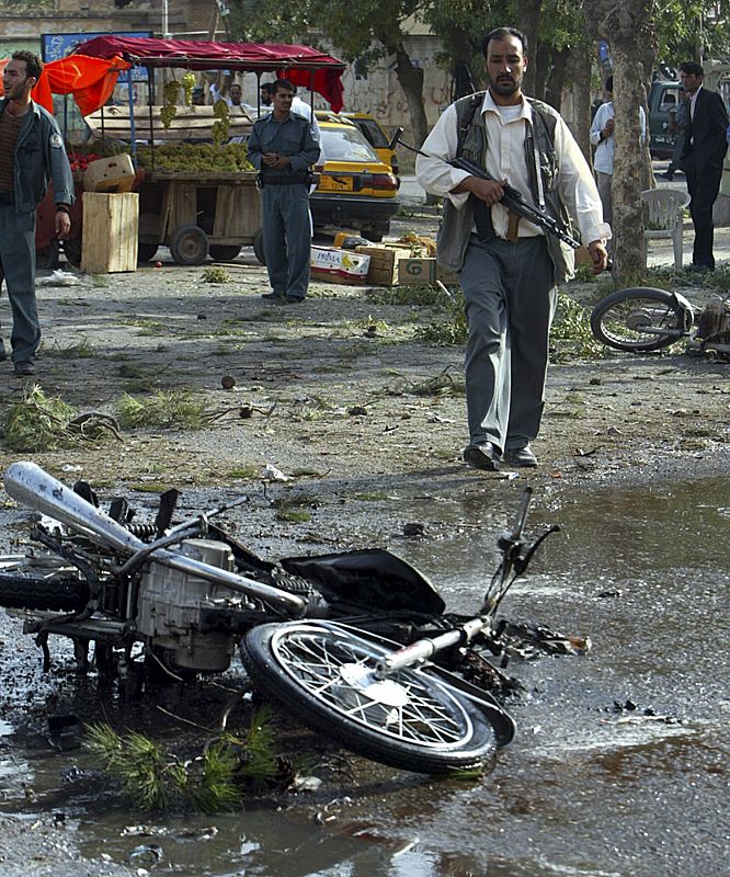 A security personnel walks towards a damaged motorcycle after a roadside bomb blast in the western city of Herat