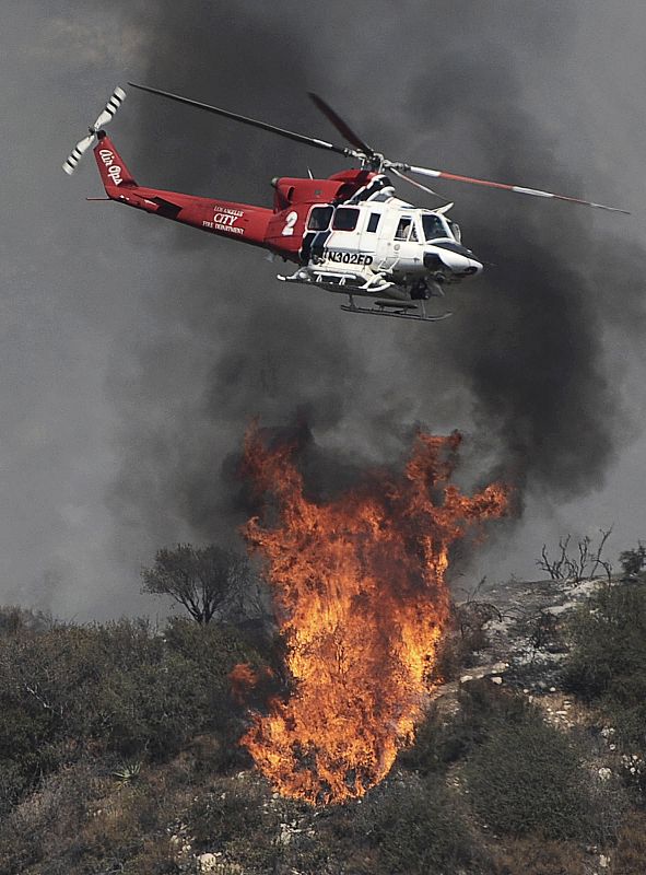 Un helicóptero de los bomberos lucha por extinguir el fuego, que cerca Los Ángeles.