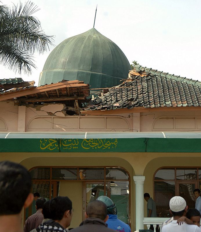 Residents gather outside a mosque damaged by a powerful earthquake at Cisaat village