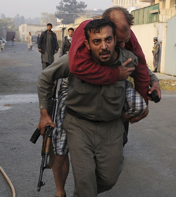 Un policía afgano carga con un herido en lugar del ataque talibán en Kabul.