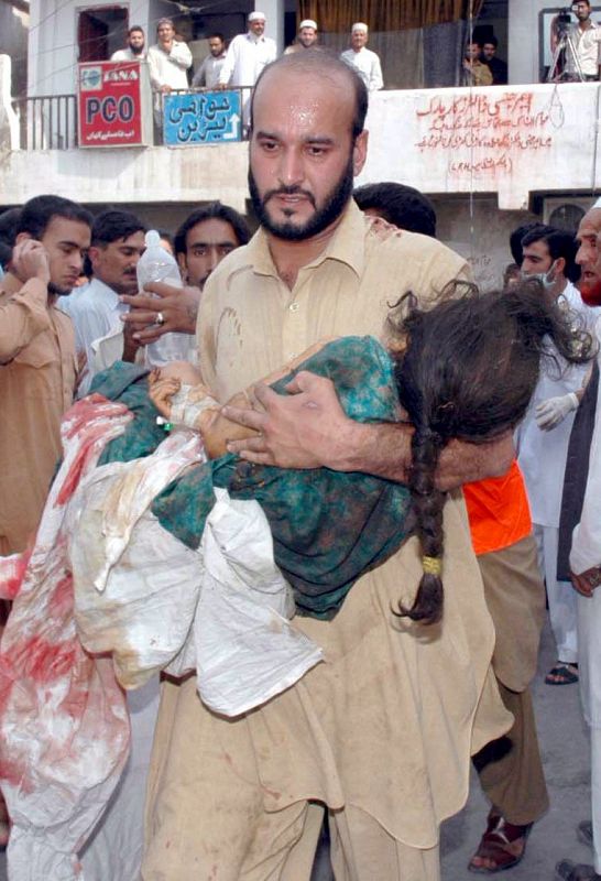 Un hombre transporta a una niña herida durante la explosión de un coche bomba en un mercado en Peshawar.