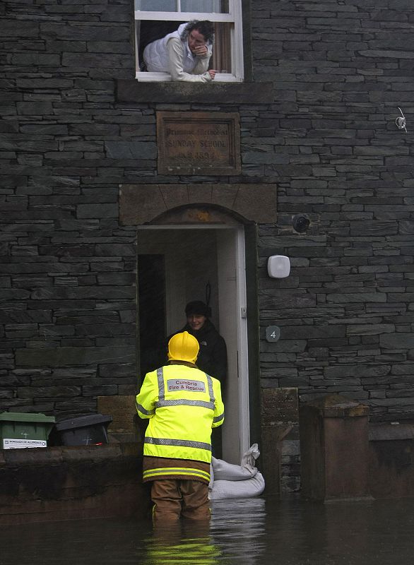 A firefighter talks to residents as he stands in flood water in Keswick