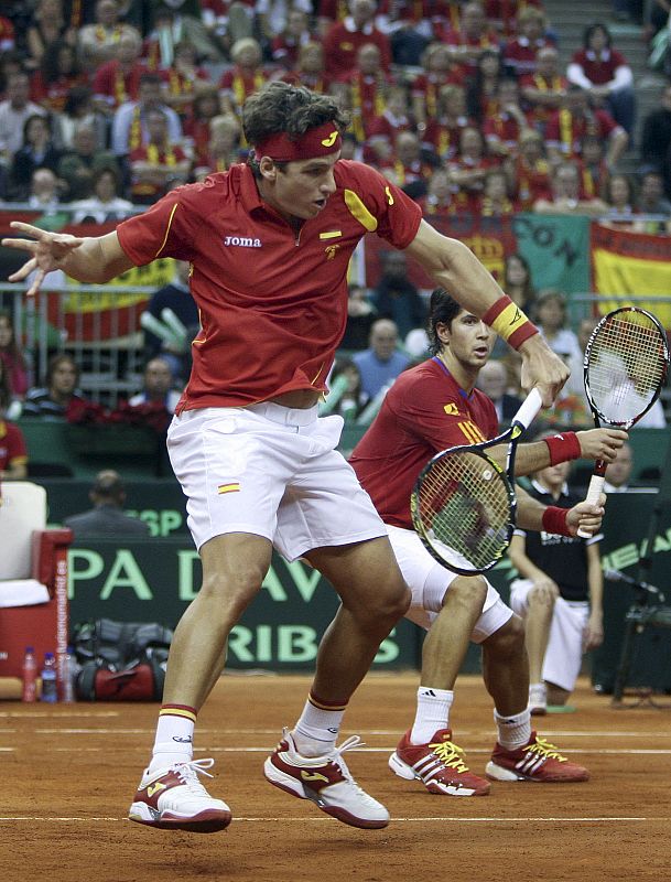 El tenista español Feliciano López se dispone a golpear una pelota, ante la atenta mirada de su compañero Fernando Verdasco.