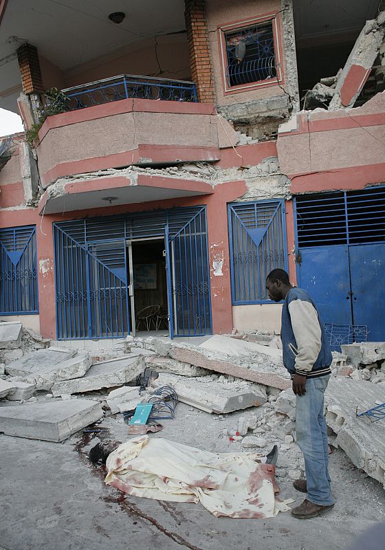 A man looks at a dead body after an earthquake in Port-au-Prince