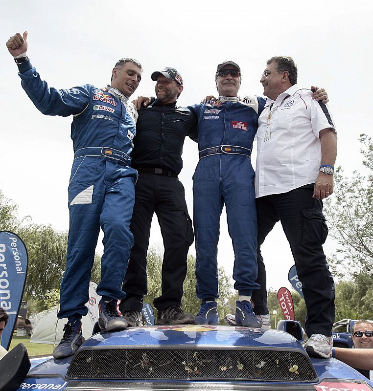 Sainz celebra la victoria con su copiloto Lucas Cruz y dos miembros del equipo Volkswagen sobre el capó de su Tuareg.