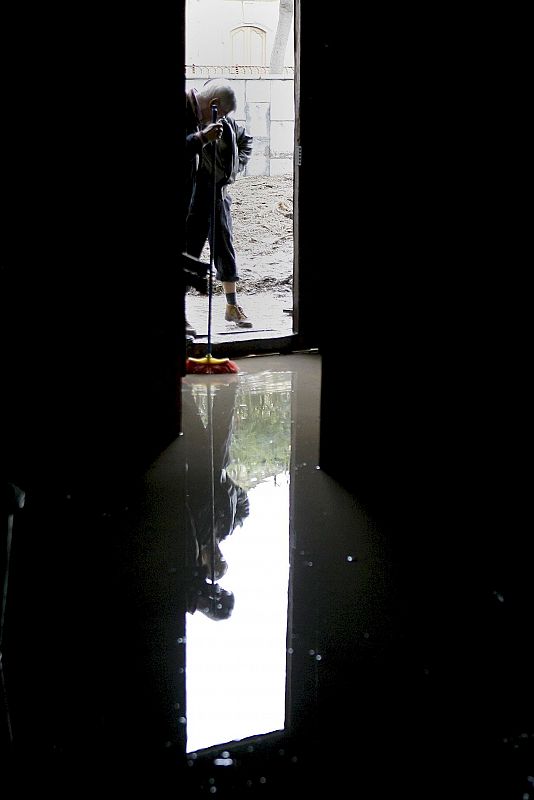 Dos vecinos achican agua del interior de la iglesia de La Concepción de la capital tinerfeña inundada tras desbordarse el barraco de Santos.