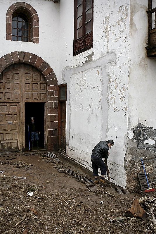 Un hombre desatasca las alcantarillas de la iglesia de La Concepción de Santa Cruz, inundada tras desbordarse el barraco de Santos.