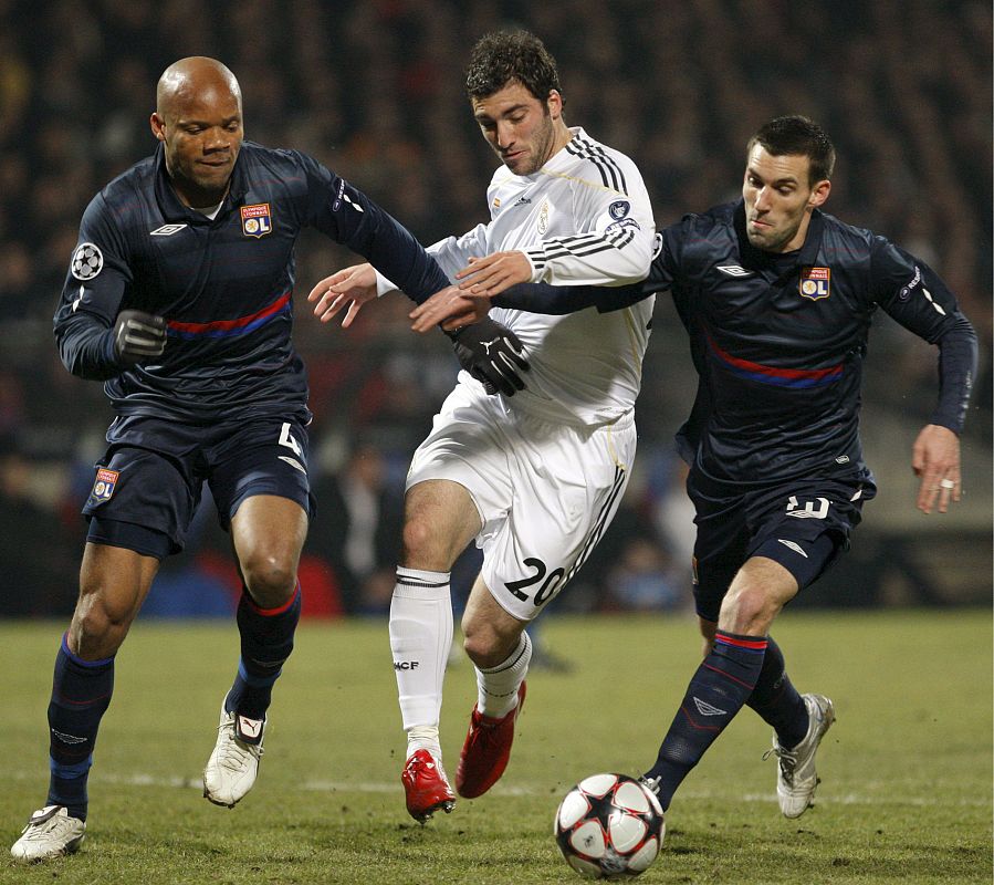 El delantero argentino del Real Madrid Gonzalo Higuaín intenta escapar con el balón de Jean-Alain Boumsong y Anthony Reveillere.