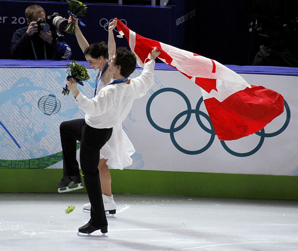 Canada's Virtue and Moir skate with their country's flag after medals ceremony for ice dance figure skating event at Vancouver Winter Olympics