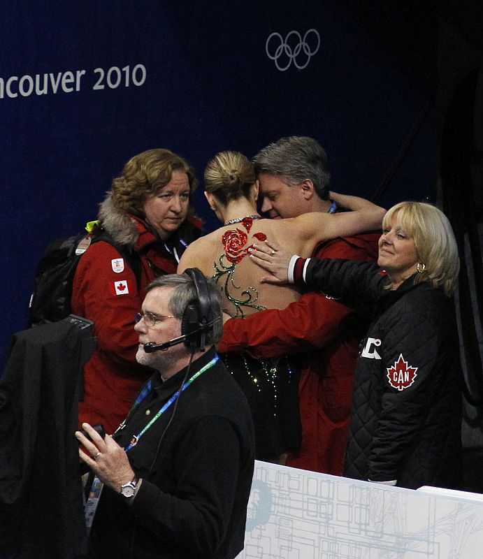 Canada's Rochette leaves rink accompanied by her coach Perron and doctor Alleyne after performing in women's short programme figure skating event at Vancouver 2010 Winter Olympics