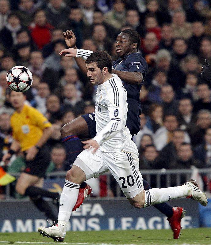 El delantero del Real Madrid, Gonzalo Higuaín y el defensa del Olympique de Lyon, Aly Cissokho.