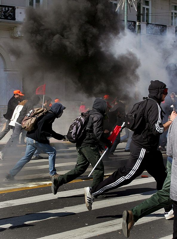 Manifestantes tratan de esquivar el gas lacrimógeno lanzado por los policías antidisturbios.