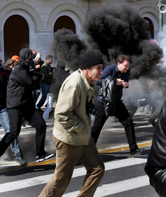 Manifestantes tratan de esquivar el gas lacrimógeno lanzado por los policías antidisturbios durante una protesta en el centro de Atenas, Grecia, hoy 11 de marzo de 2010.