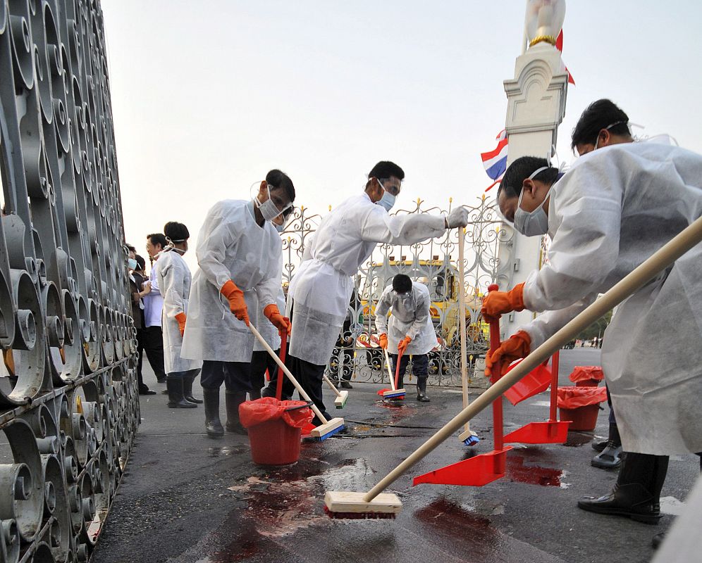 Varios operarios limpian la sangre arrojada por manifestantes opositores la Gobierno ante las puertas de la sede del Gobierno en Bangkok