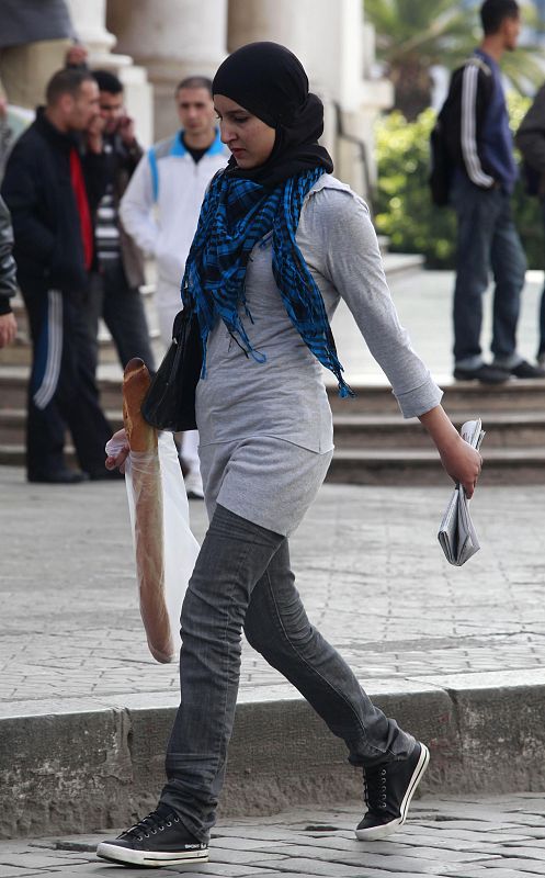 Una joven estudiante viste pantalones vaqueros y zapatillas deportivas que contrastan con el 'hiyab' de su cabeza.