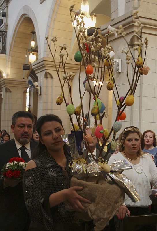 A woman carries a gift as she attends Easter mass at St. Paul's Franciscan church and monastery in Damascus