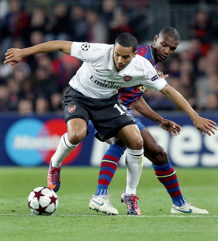 El defensa francés del FC Barcelona Eric Abidal y el centrocampista del Arsenal, Theo Walcott luchan por el balón.