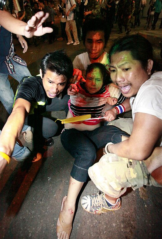 An injured woman is carried following several small explosions in the business district of Bangkok