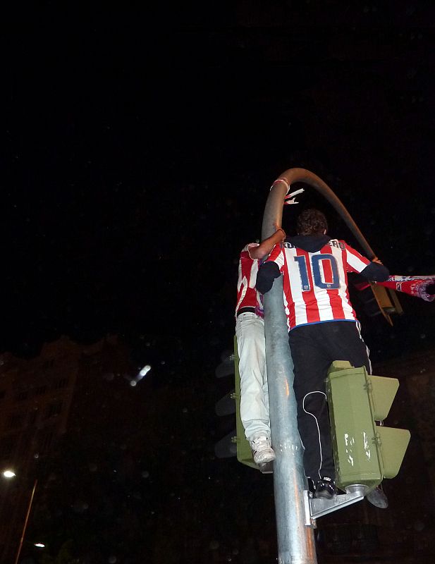 Dos aficionados del Atleti, encaramados a un semáforo, festejan la consecución de la Europa League.