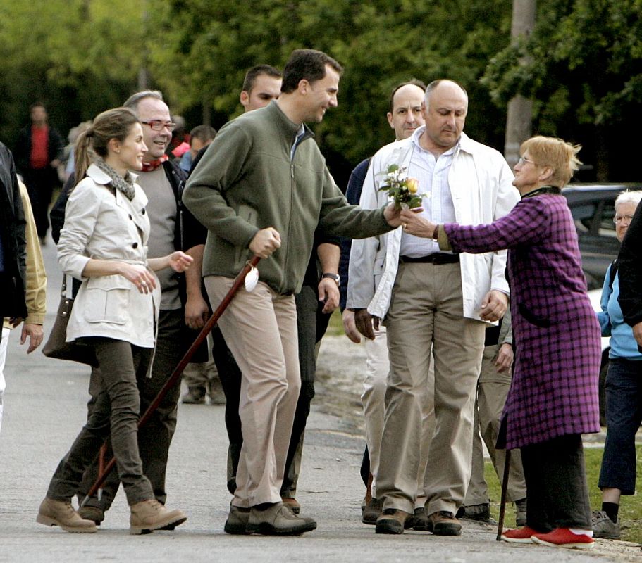 Los Príncipes de Asturias reciben de manos de una vecina de Monte Gozo, unas flores durante el recorrido del último tramo del Camino Francés hasta la Catedral de Santiago.