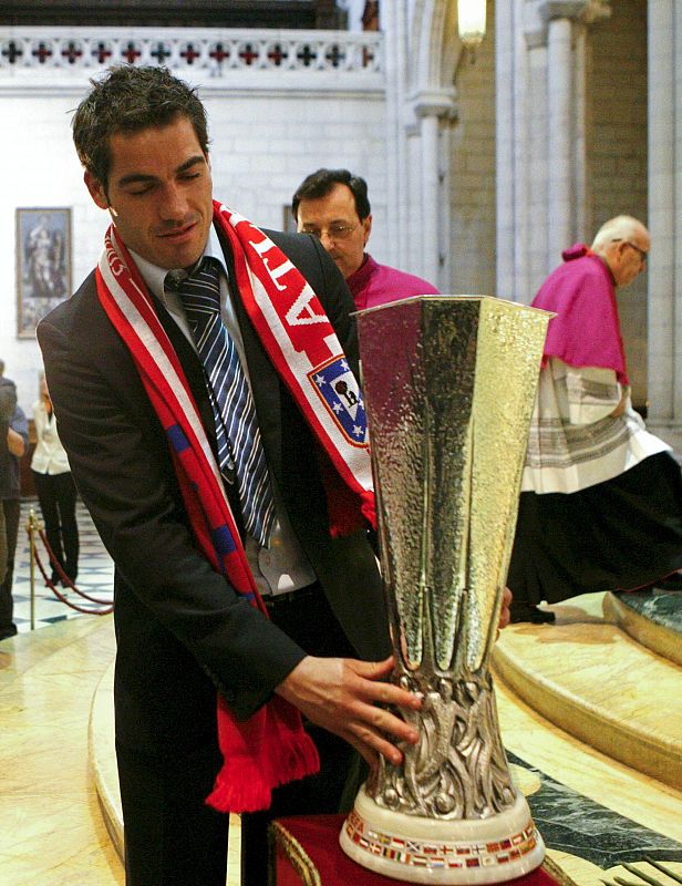 El capitán del Atlético de Madrid Antonio López porta la copa de la Liga Europa, en la catedral de La Almudena, para celebrar la habitual ofrenda a la patrona.