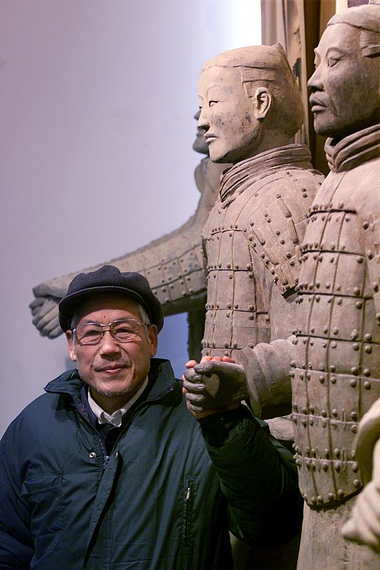 Chinese farmer Yang Zhifa, 63, poses with replicas of his discovery which kicked off one of the grea..