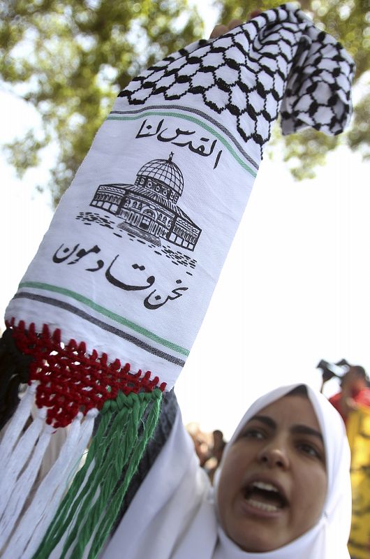 A woman holds a scarf with an Arabic inscription "Jerusalem, we are coming" while chanting anti-Israeli slogans in front of the Egyptian Foreign Ministry in Cairo