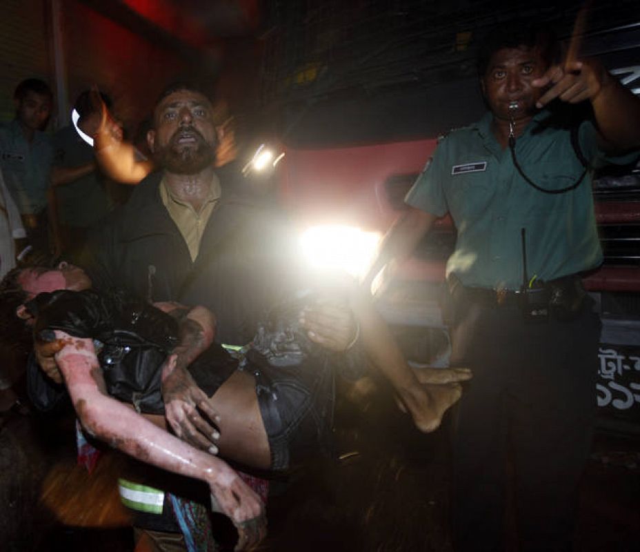 A man recovers the body of a victim from the site of a fire in the old part of Dhaka