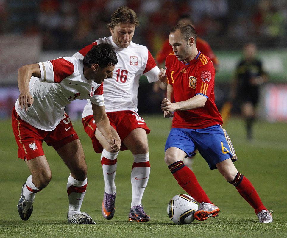 Spain's Iniesta fights for the ball with Poland's Dudka and Blaszczykowski during a friendly soccer match in Murcia