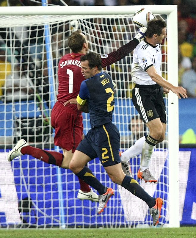 Miroslav Klose de Alemania remata de cabeza para conseguir el 2-0 ante los australianos Lucas Neill y Mark Schwarzer.