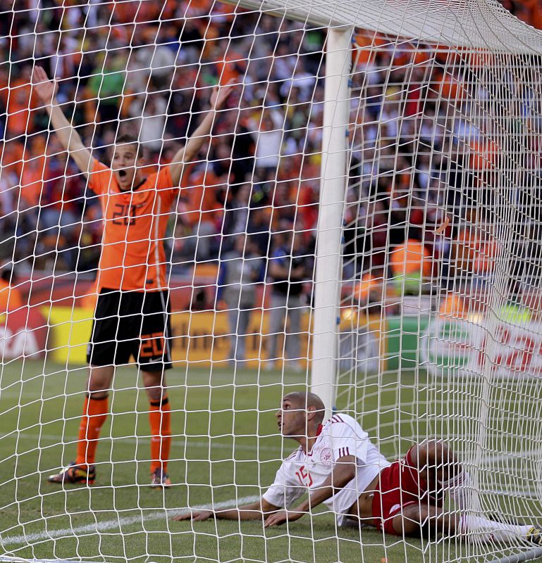 El jugador danés Poulsen sólo puede mirar el balón dentro de su portería mientras Afellay, de Holanda, celebra el tanto.