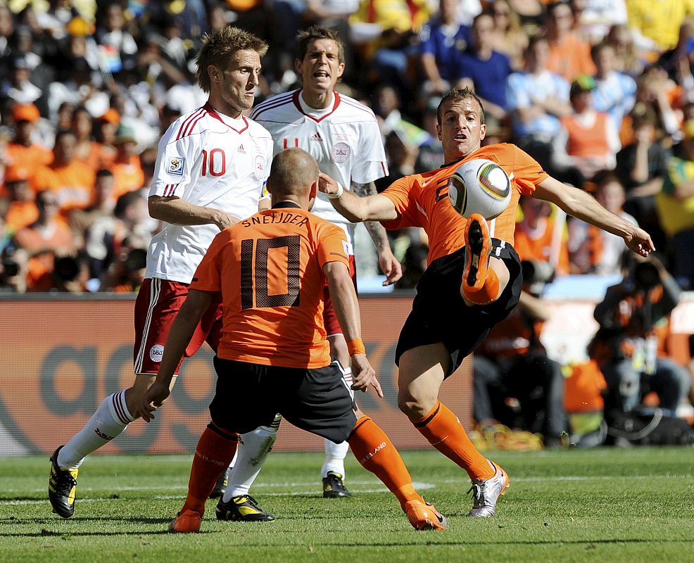 El centrocampista holandés Rafael van der Vaart (d) controla el balón en presencia de su compañero Wesley Sneijder (10) y de Martin Jorgensen (i) de Dinamarca.