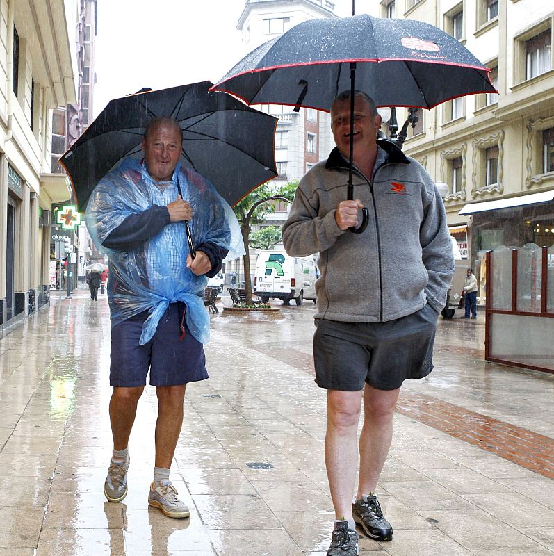 Dos turistas pasean bajo las abundantes lluvias que se están registrando en toda la córnisa cantábrica, originando diversos problemas de inundaciones y comunicaciones por carretera y ferrocarril.