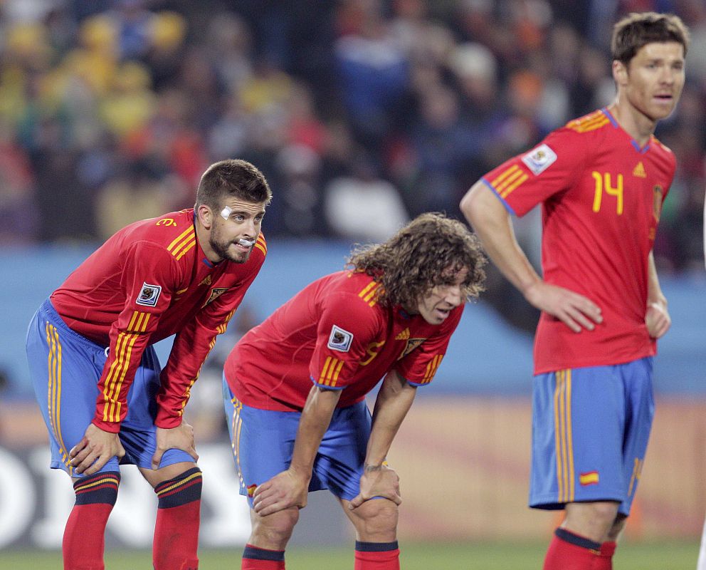 Spain's Gerard Pique, teammates Carles Puyol and Xabi Alonso take a breather as they await a substitution in Johannesburg