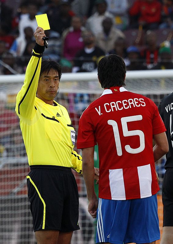 El colegiado japonés Yuichi Nishimura muestra la tarjeta amarilla al paraguayo Victor Cáceres.