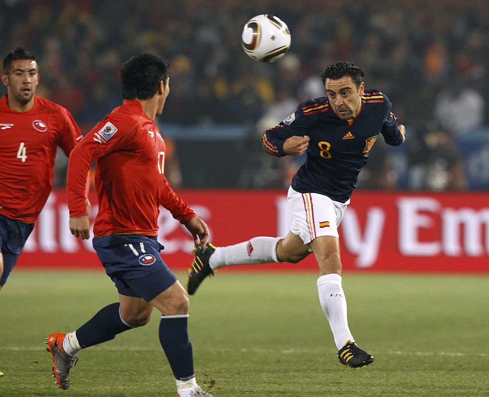 Spain's Xavi heads the ball as Chile's Isla and Medel look on during a 2010 World Cup Group H match at Loftus Versfeld stadium in Pretoria