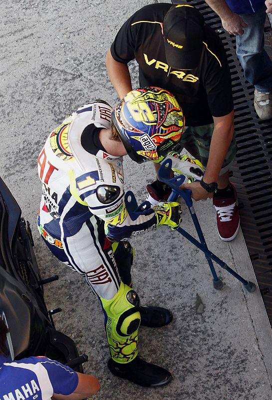 Valentino Rossi recibe las muletas de su amigo Uccio después de bajarse de la moto.